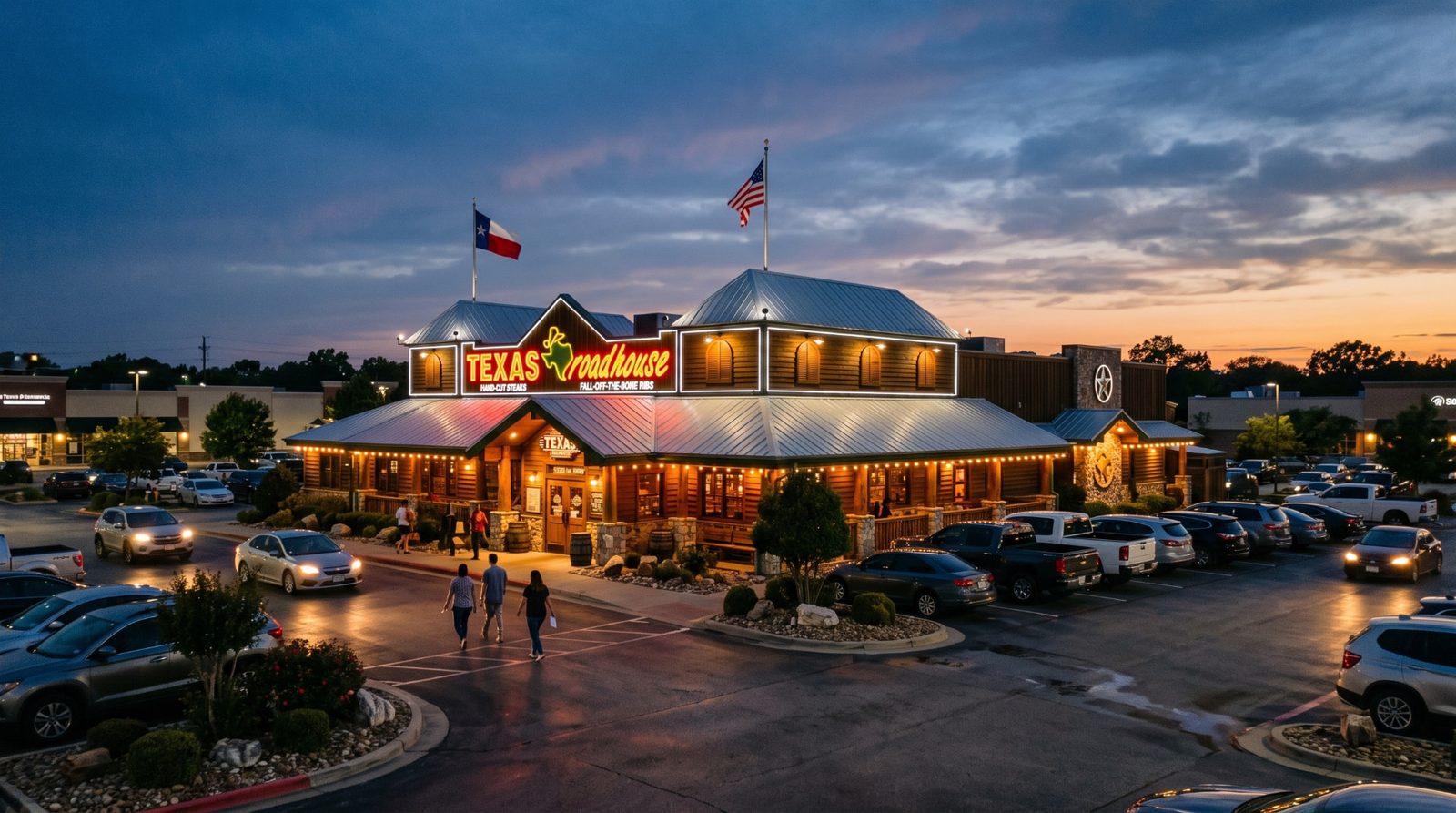 Texas Roadhouse restaurant exterior lit up at dusk with guests walking through the parking lot